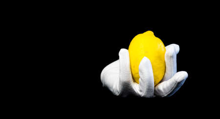 White glove with the ripening wet lemon on a black background