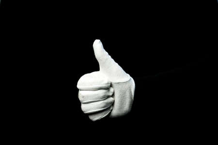 A hand wearing white glove on black background showing that everything is okの写真素材