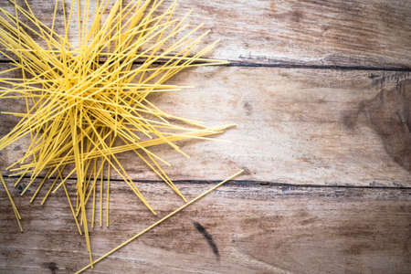 Uncooked spaghetti pasta isolated on vintage wooden tableの写真素材