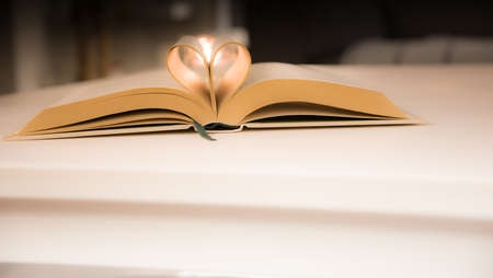 The old book opens, and the book page rolls into the heart colorful background selective focus and shallow depth of fieldの写真素材