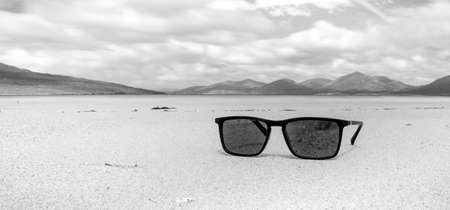 Sunglasses on sandy beach in summer - black and whiteの写真素材