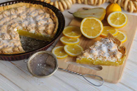 Fresh homemade lemon tart for Breakfast with a slice of lemon for a simple light wooden background.の写真素材