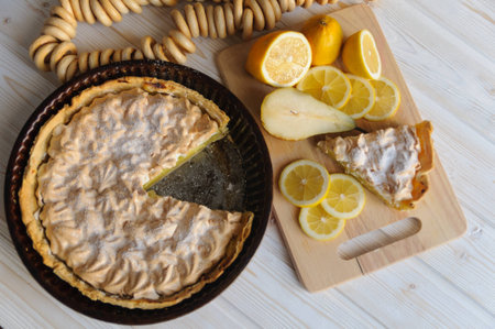 Fresh homemade lemon tart for Breakfast with a slice of lemon for a simple light wooden background.の写真素材