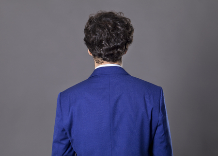 Young man with curly hair standing back to cameraの写真素材