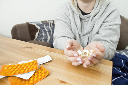 Woman taking medicine capsules at homeの写真素材