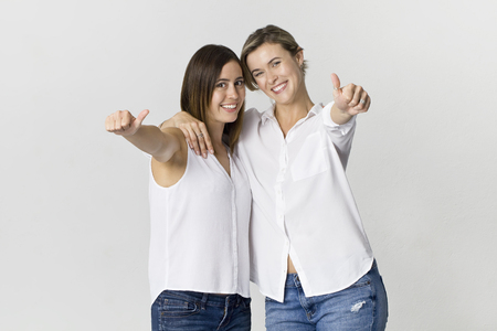 Two girlfriends having fun at studio background. Two young women smiling portraitの写真素材