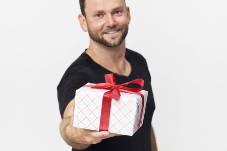 Smiling handsome man with a gift box standing against white backgroundの写真素材