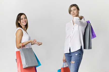 Two beautiful female friends on shopping with colorful bags. Toothy smile two young women portraitの写真素材