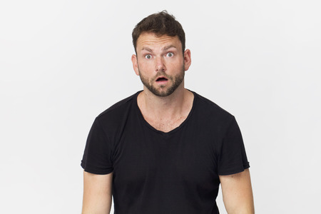 Surprised young handsome man wearing black t-shirt, isolated on white