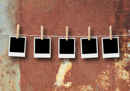 Old picture frame hanging on clothesline on background.