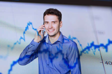 Smiling man talking by mobile phone and diagrama on foregroundの写真素材