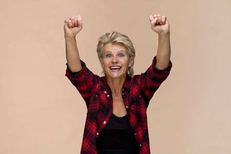 Happy blonde woman smiling portrait victory gesture against colored background