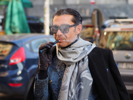MILAN - JANUARY 14: Elegant man smoking the pipe before DAKS fashion show, during Milan Fashion Week Man fall / winter 2018/19 on January 14, 2018 in Milan.のeditorial素材