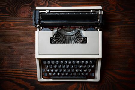 Old typewriter on wooden table with a blank bloc notesの写真素材