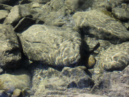 Nature background of transparent river water with stones