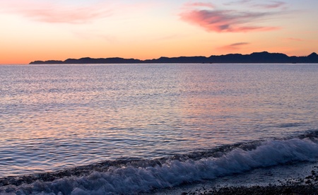 Sunrise on beach looking toward Carmen Island with clouds.