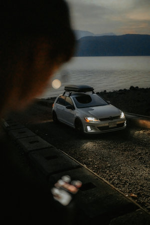 Man looking at the sea through the window of his car in the eveningの写真素材