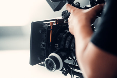 Close-up of professional videographer holding professional camera. Filmmaking equipment.