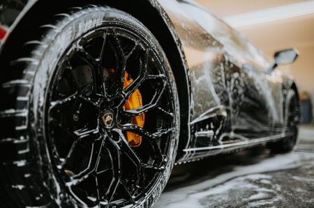 Close up of a black sports car with splashes of water.の写真素材