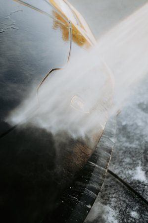 Cleaning car with high pressure water. Shallow depth of field.