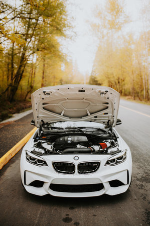 Car with open hood on the road in autumn forest. Auto service conceptの写真素材
