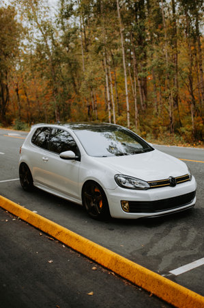 White car on the road in the autumn forest. Side view.のeditorial素材