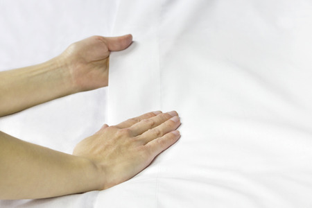 A pair of hands smoothing out a bed sheet.の写真素材