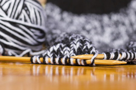 Wooden knitting needles with black and white wool, on a wooden surface.の写真素材