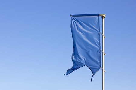 Blue flag raised over a cloudless blue sky.の写真素材