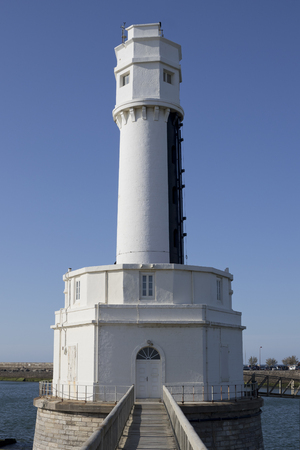 Small white lighthouse in a platform with a stone bridge access (Angle, France).の写真素材