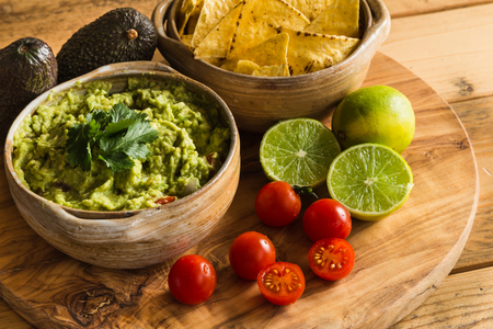 Guacamole dip in bowl with tortilla chips and ingredientsの写真素材