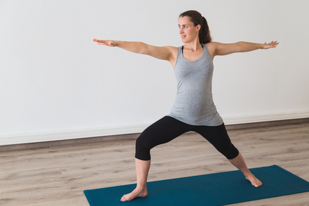 Young woman doing prenatal yoga in warrior two poseの写真素材