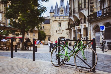 Bordeaux, France - Green bicycle locked to railing with Port Cailhau in the background.のeditorial素材