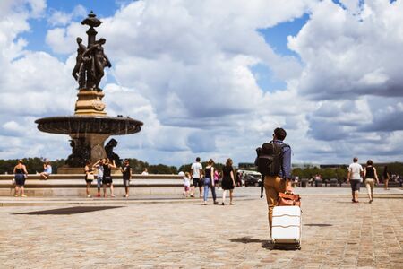 Bordeaux, France - Tourist crosses the Place de la Bourse carrying his luggage whilst looking at the fountain.のeditorial素材