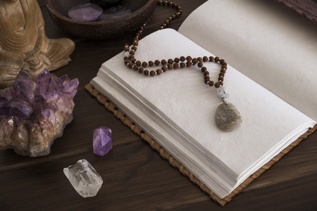 Open leatherbound writing journal or notebook surrounded by crystals on a wooden surfaceの写真素材