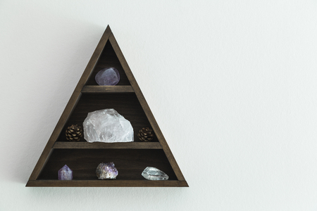 Triangular wooden crystal shelf hung on wallの写真素材