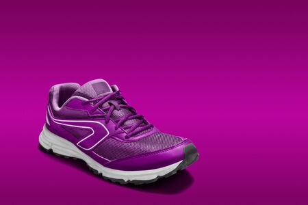 View of a single fushia pink sport shoe, for running, exercise or leisure on a matching colored backdground.の写真素材