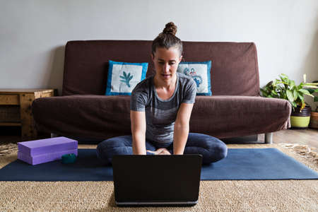 Yoga instructor or student in downward facing dog posture participating in online video lesson over...