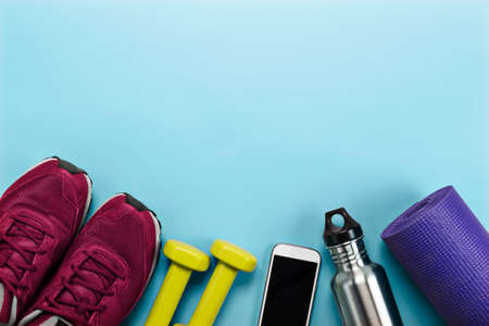 Sports equipment including running shoes, yoga mat, water bottle and cellphone.