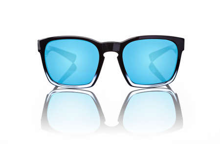 Pair of sunglasses with blue tinted lenses and black frames on white background with reflection, shot directly from the front.の写真素材