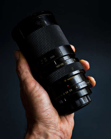 Old vintage telephoto lens with scratches and marks on a dark studio background