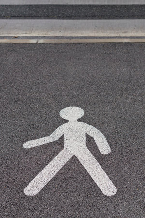 Sign painted in white on the ground of a walking stick figure showing a pedestrian crossing pointの写真素材
