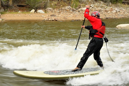 A stand up paddleboard surfer frozen in time using a slow shutter speed as the river flows past.の写真素材