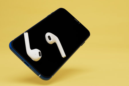listening to music in headphones. smartphone and wireless headphones on a yellow background. 3D rendering.の写真素材
