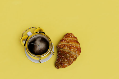time for breakfast. a cup of coffee in the form of an alarm clock and a croissant on a yellow background. 3D rendering.の写真素材