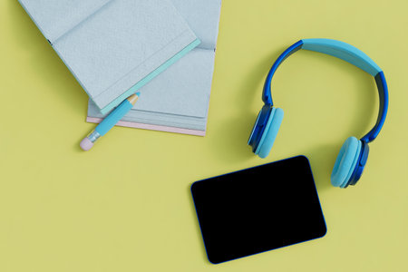 audiobook training. books, pencil, headphones and tablet on a yellow background. 3D rendering.の写真素材