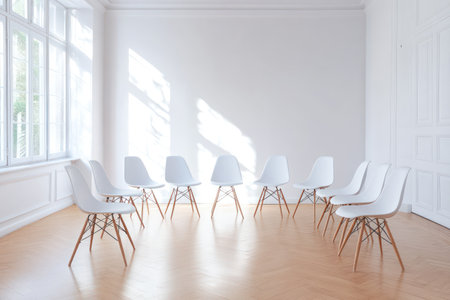 Bright white room with wooden floor and chairs arranged in a circle, representing discussion, therapy, meetings, or support group.の素材