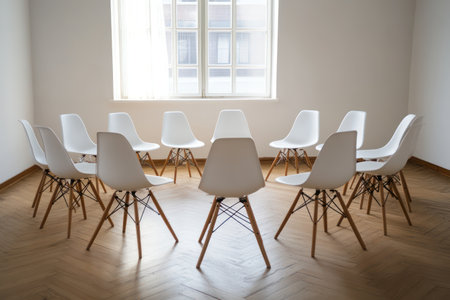 Bright white room with wooden floor and chairs arranged in a circle, representing discussion, therapy, meetings, or support group.の素材