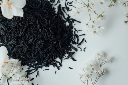 Close-up of dried black tea leaves spread across a clean white surface, perfect for packaging, culinary, or health concepts.の素材