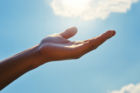 Symbolic image of Jesus' hand reaching out under a blue sky, representing hope, kindness, faith, and compassion.の素材